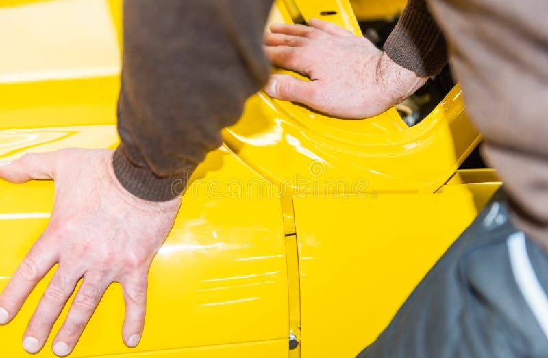 Los mecánicos de coche alinean el capo correctamente al montar - taller de la reparación de Serie imágenes de archivo libres de regalías Los mecánicos de coche alinean el capo correctamente al montar - taller de la reparación de Serie imágenes de archivo libres de regalías