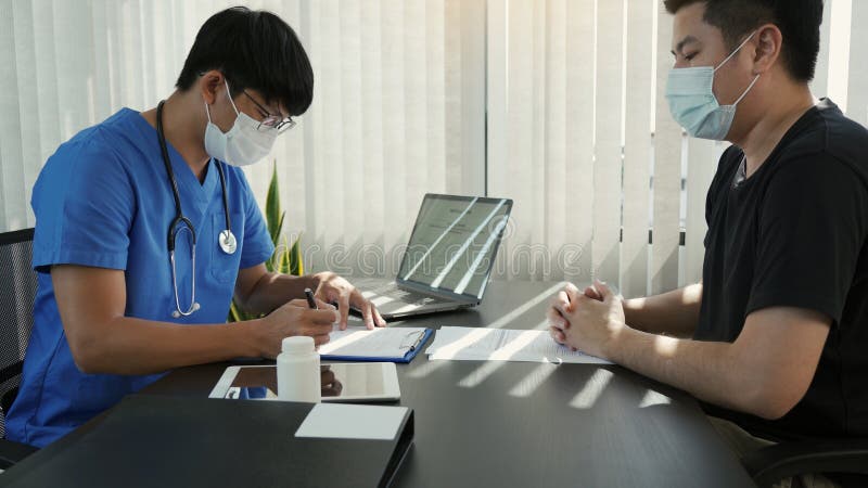 Los médicos están explicando el tratamiento de una enfermedad en pacientes que llevan una máscara durante la epidemia imagenes de archivo