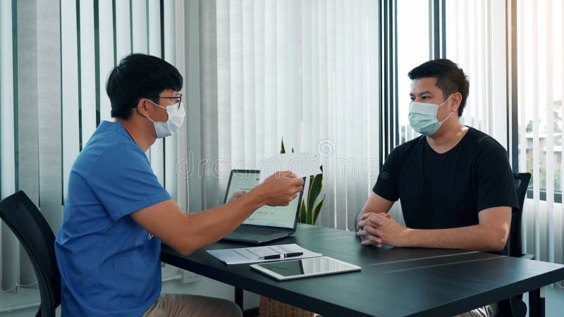 Los médicos están explicando el tratamiento de una enfermedad en pacientes que llevan una máscara durante la epidemia imagen de archivo libre de regalías