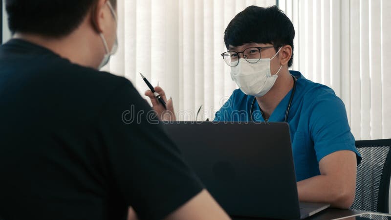 Los médicos están explicando el tratamiento de una enfermedad en pacientes que llevan una máscara durante la epidemia fotografía de archivo