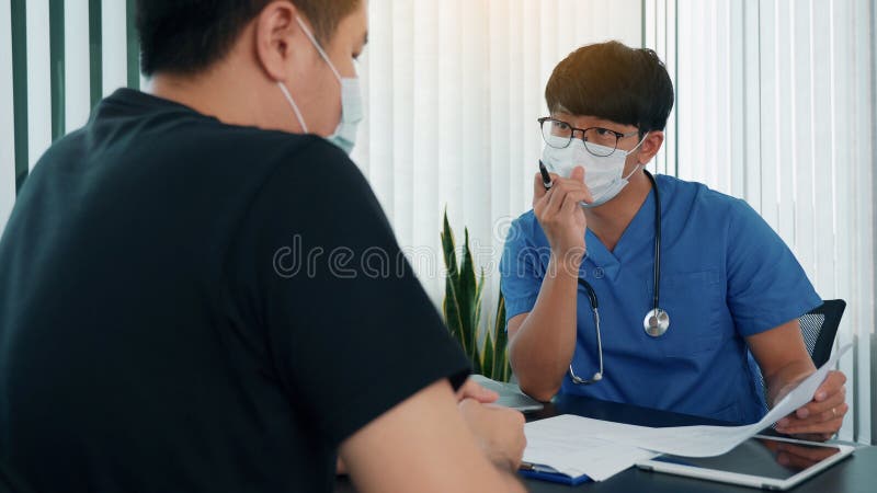 Los médicos están explicando el tratamiento de una enfermedad en pacientes que llevan una máscara durante la epidemia imagen de archivo libre de regalías