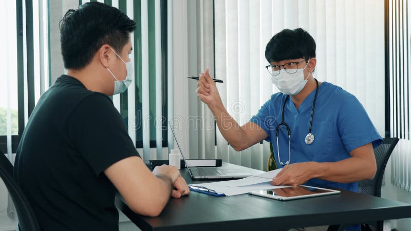 Los médicos están explicando el tratamiento de una enfermedad en pacientes que llevan una máscara durante la epidemia fotos de archivo libres de regalías