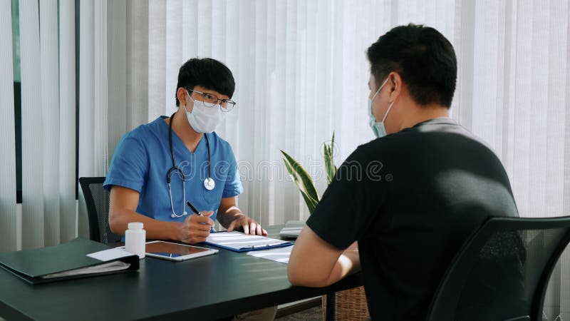 Los médicos están explicando el tratamiento de una enfermedad en pacientes que llevan una máscara durante la epidemia imágenes de archivo libres de regalías