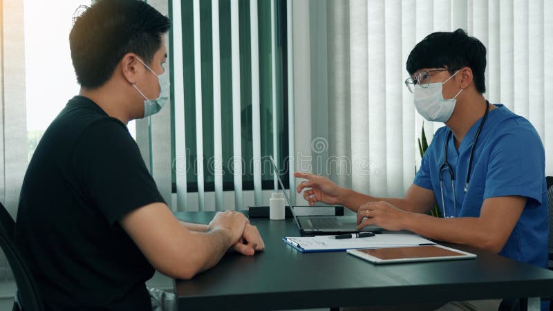 Los médicos están explicando el tratamiento de una enfermedad en pacientes que llevan una máscara durante la epidemia foto de archivo libre de regalías
