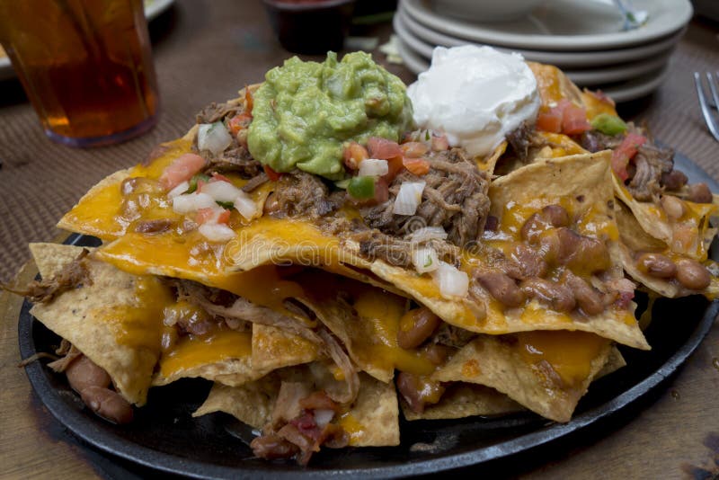 Layered brisket nachos with sour cream, guacamole, black beans, cheese and jalapenos. Layered brisket nachos with sour cream, guacamole, black beans, cheese and jalapenos
