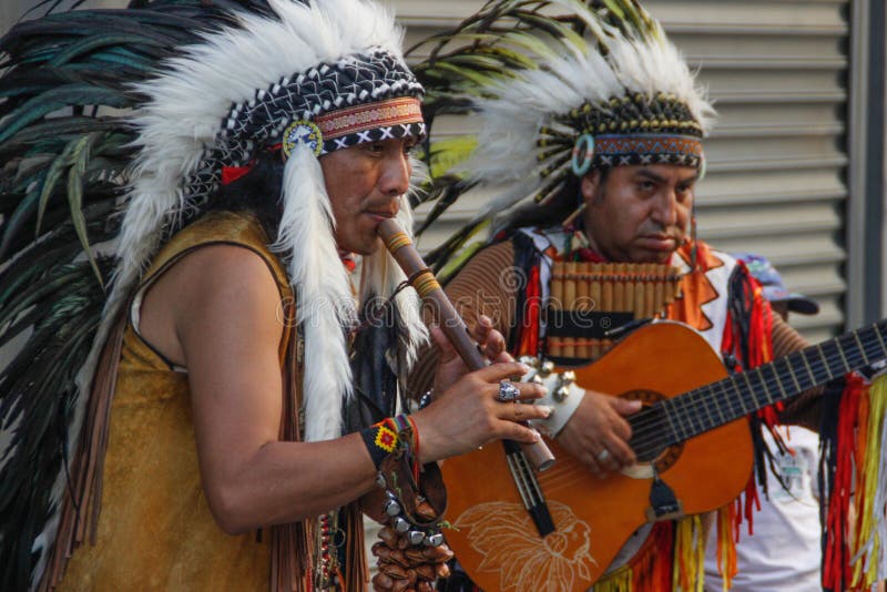 Los nativos americanos rojos de los indios tocan la flauta y la guitarra en tocados de la pluma