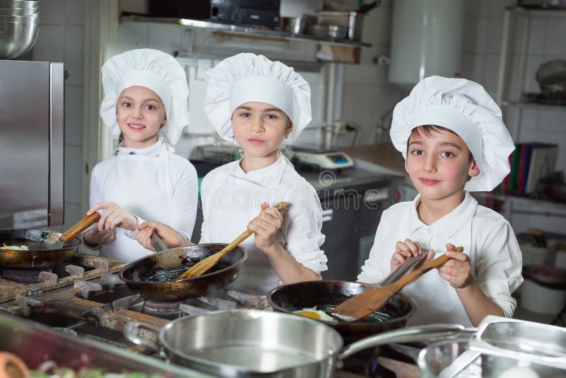Los niños cocinan huevos en la cocina del restaurante. imagen de archivo libre de regalías