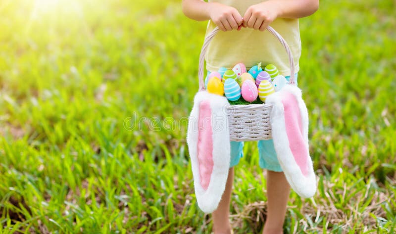 Los niños con la cesta de los huevos en el huevo de Pascua cazan