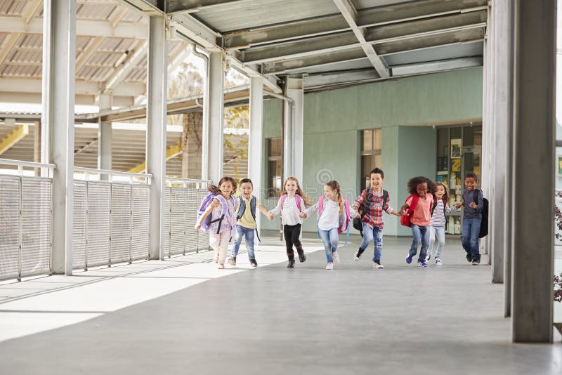 Los niños de la escuela primaria corren llevar a cabo las manos en pasillo de la escuela imagen de archivo libre de regalías Los niños de la escuela primaria corren llevar a cabo las manos en pasillo de la escuela imagen de archivo libre de regalías