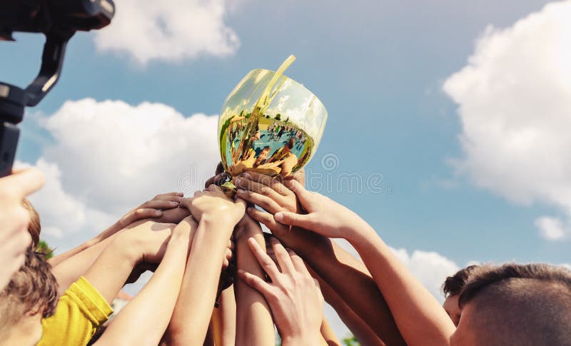 Los niños en el equipo deportivo levantan el trofeo de la copa de oro después de ganar el partido final del torneo