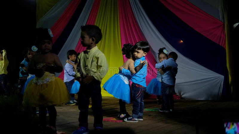 Los niños gozan el bailar juntos en etapa