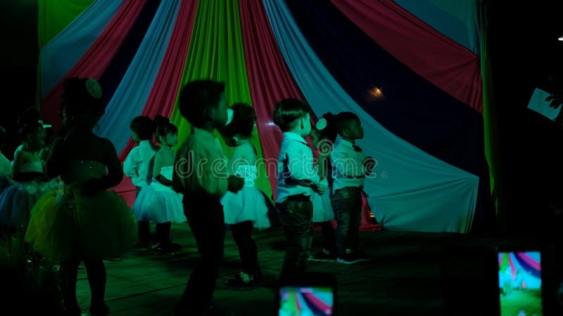 Los niños gozan el bailar juntos en etapa