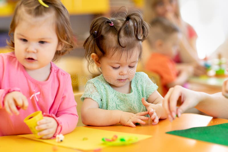 Los niños pequeños se divierten con la arcilla de modelado colorida en la guardería Los niños juegan con plasticina o masa imagen de archivo Los niños pequeños se divierten con la arcilla de modelado colorida en la guardería Los niños juegan con plasticina o masa imagen de archivo