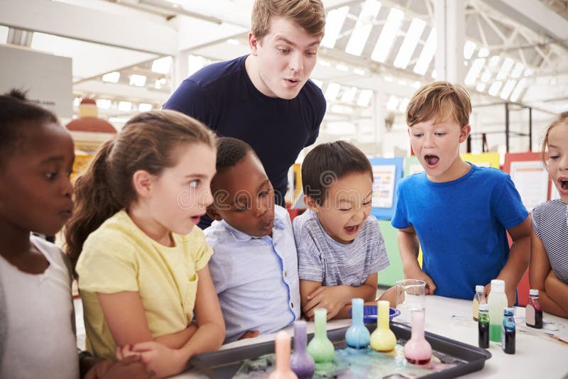Los niños y el profesor de la escuela miran el experimento en un centro de la ciencia