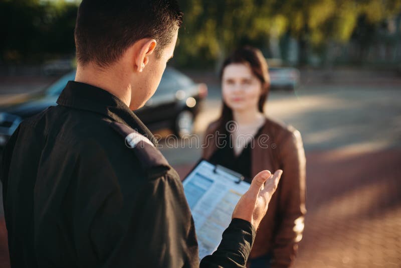 Los oficiales de policía leen ley al conductor femenino fotos de archivo libres de regalías Los oficiales de policía leen ley al conductor femenino fotos de archivo libres de regalías