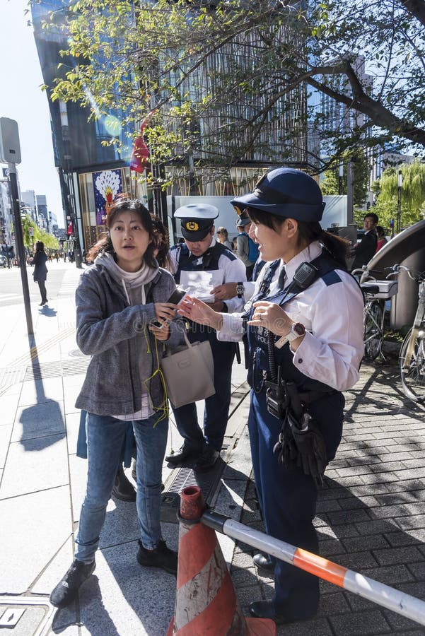 Los oficiales de policía que ayudan a la mujer encuentran la manera Ginza Tokio fotografía de archivo Los oficiales de policía que ayudan a la mujer encuentran la manera Ginza Tokio fotografía de archivo