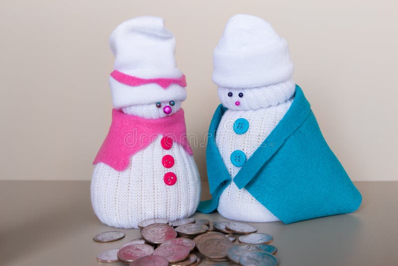 Los pares de los muñecos de nieve del juguete miran la pila de monedas fotografía de archivo Los pares de los muñecos de nieve del juguete miran la pila de monedas fotografía de archivo