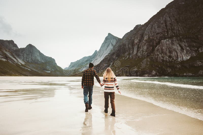 Los pares en el amor que camina llevando a cabo las manos en el mar salvaje varan foto de archivo libre de regalías Los pares en el amor que camina llevando a cabo las manos en el mar salvaje varan foto de archivo libre de regalías