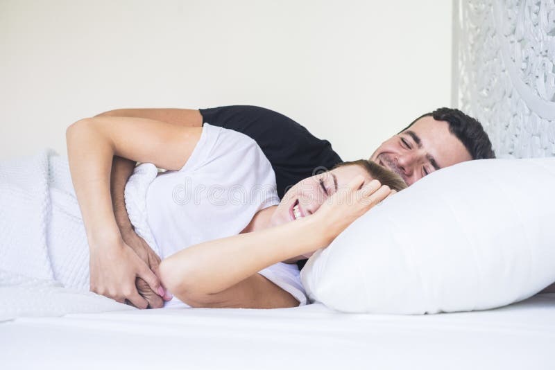 Los pares jovenes felices colocan y durmiendo o despertando en la madrugada en casa dormitorio blanco en casa y gente que abraza foto de archivo Los pares jovenes felices colocan y durmiendo o despertando en la madrugada en casa dormitorio blanco en casa y gente que abraza foto de archivo