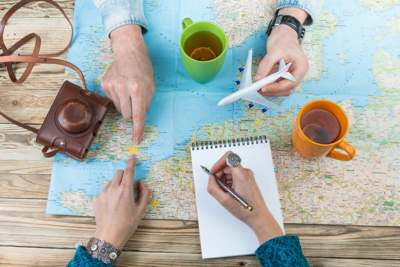 Young couple planning a family trip to London. exploring the map, develop the perfect travel itinerary . Top view wooden table. Young couple planning a family trip to London. exploring the map, develop the perfect travel itinerary . Top view wooden table