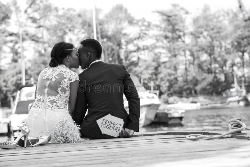 Los pares románticos que se sientan en un muelle de madera y expresan su amor fotografía de archivo libre de regalías Los pares románticos que se sientan en un muelle de madera y expresan su amor fotografía de archivo libre de regalías