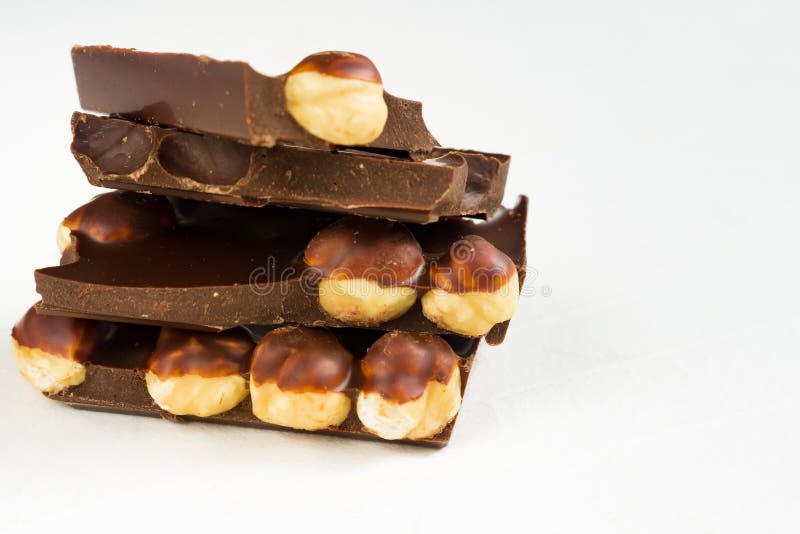 Los pedazos oscuros del chocolate de la avellana se elevan en el fondo blanco imagen de archivo Los pedazos oscuros del chocolate de la avellana se elevan en el fondo blanco imagen de archivo