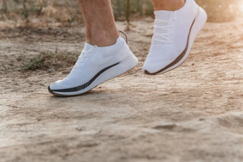 Los De Los Hombres En Las Zapatillas De Deporte Blancas Que Corren Sobre Terreno áspero Campo a Través Que Corre Con El de - Imagen de atleta, zapato: