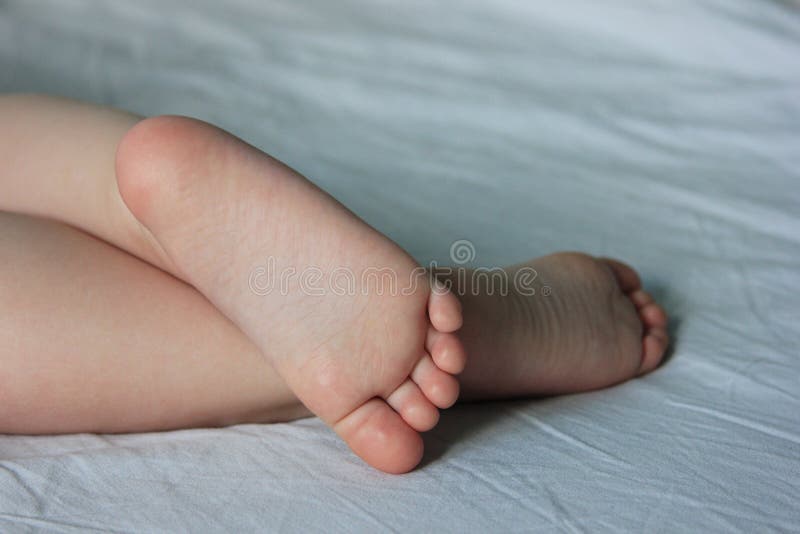 Los pies del bebé lindo El niño está durmiendo en la cama primer imágenes de archivo libres de regalías Los pies del bebé lindo El niño está durmiendo en la cama primer imágenes de archivo libres de regalías
