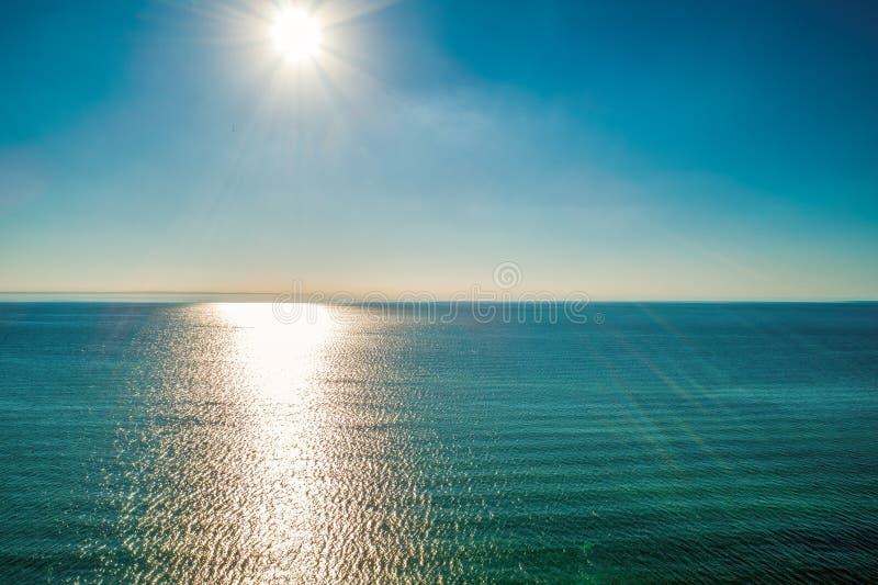 Los rayos solares brillantes sobre el agua de mar tranquila