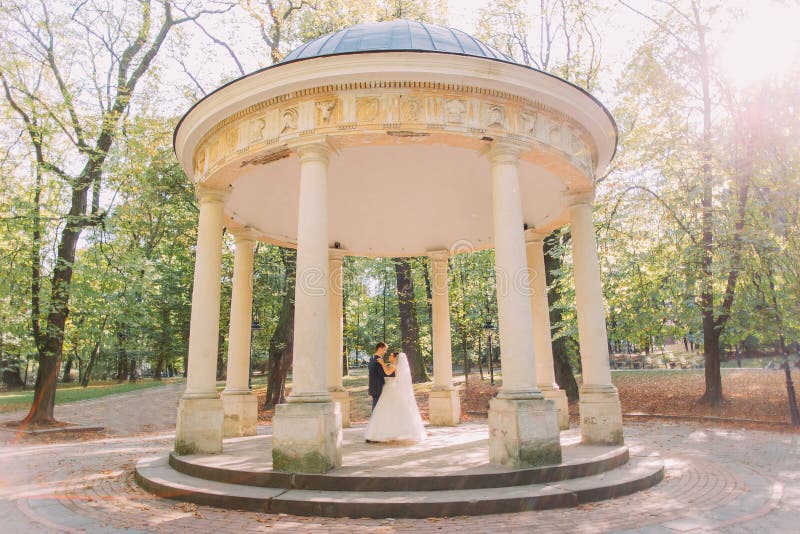 Los recienes casados del baile en la alcoba vieja colocada en el parque soleado fotografía de archivo libre de regalías Los recienes casados del baile en la alcoba vieja colocada en el parque soleado fotografía de archivo libre de regalías