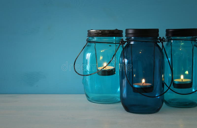 los tarros de albañil mágicos decorativos del vintage con la vela se encienden en la tabla de madera imagenes de archivo los tarros de albañil mágicos decorativos del vintage con la vela se encienden en la tabla de madera imagenes de archivo
