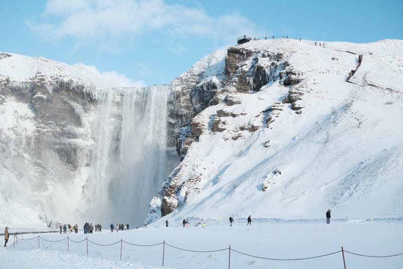 Los turistas adentro a la cascada Skogafoss de Islandia en la opinión islandesa del paisaje de la naturaleza en la estación del i imágenes de archivo libres de regalías Los turistas adentro a la cascada Skogafoss de Islandia en la opinión islandesa del paisaje de la naturaleza en la estación del i imágenes de archivo libres de regalías