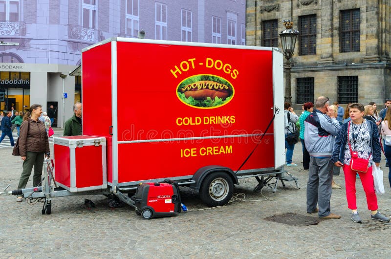 Los turistas están en Dam Square cerca de Royal Palace en Amsterdam, Países Bajos Furgoneta brillante para vender los perritos ca imagen de archivo Los turistas están en Dam Square cerca de Royal Palace en Amsterdam, Países Bajos Furgoneta brillante para vender los perritos ca imagen de archivo