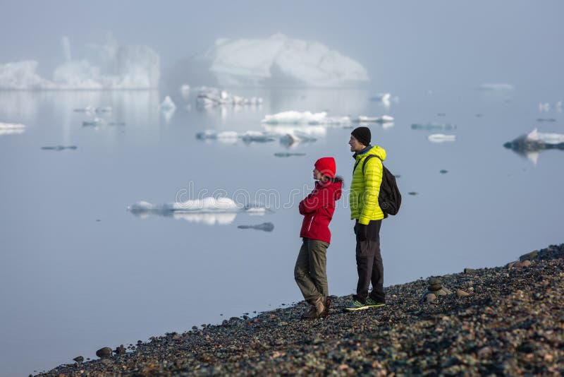 Los turistas se están oponiendo en el amanecer al contexto de las lagunas del glasser en la niebla y están admirando el paisaje fotografía de archivo libre de regalías Los turistas se están oponiendo en el amanecer al contexto de las lagunas del glasser en la niebla y están admirando el paisaje fotografía de archivo libre de regalías