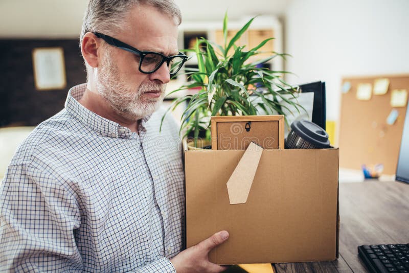 Sad quiet man looking frustrated while coming home with a heavy box full of personal items after losing his job stock photography Sad quiet man looking frustrated while coming home with a heavy box full of personal items after losing his job stock photography