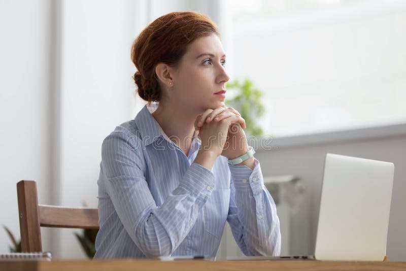 Lost in thoughts woman sits at workplace desk in office