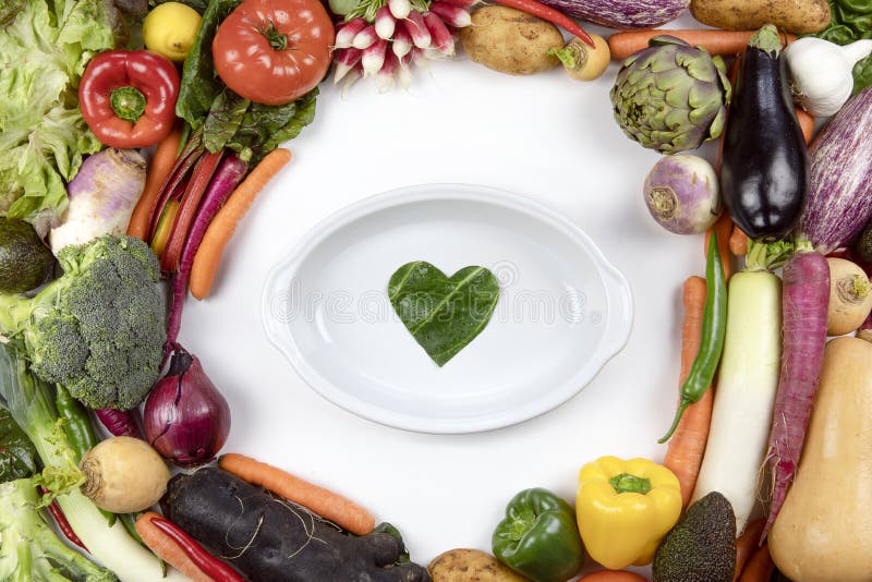 A lot of colorful fresh vegetable flat lay frame with baking dish and green heart love symbol inside. Healthy diet concept.