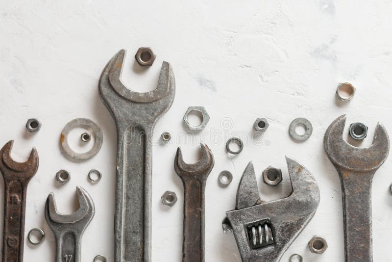 A lot of old wrenchs on a light stone background. Nuts and washers of different sizes. royalty free stock image