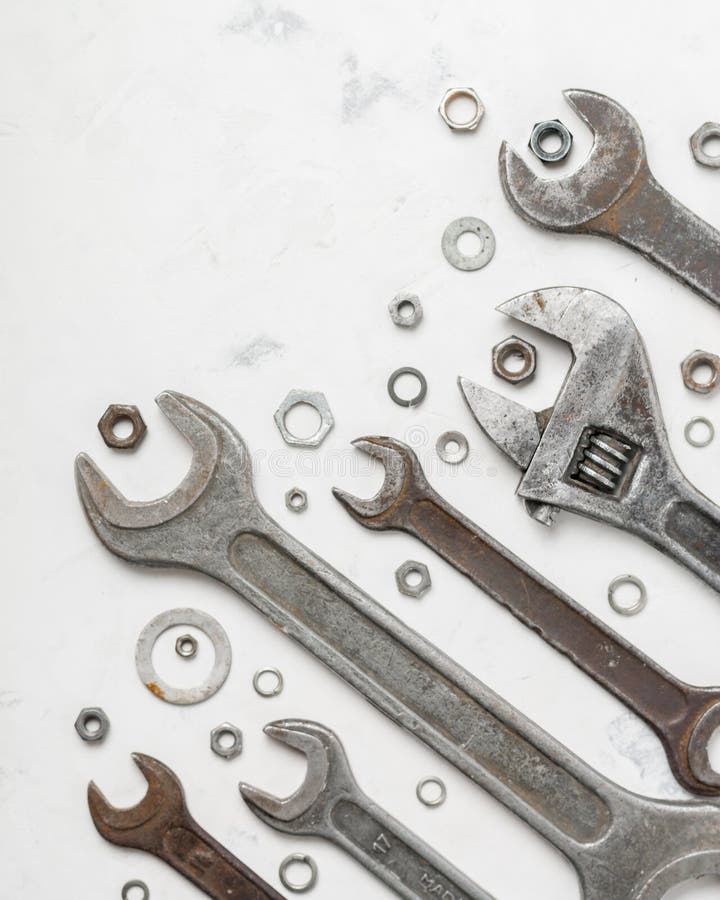 A lot of old wrenchs on a light stone background. Nuts and washers of different sizes. royalty free stock image