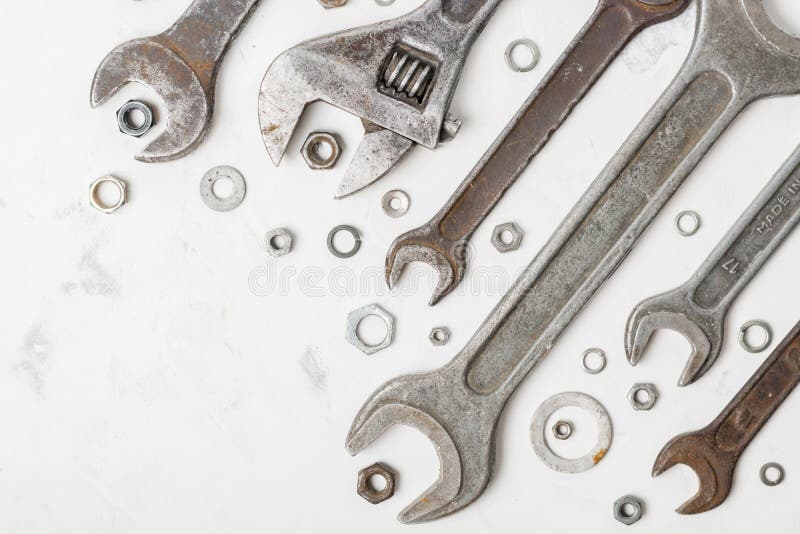 A lot of old wrenchs on a light stone background. Nuts and washers of different sizes. stock photo