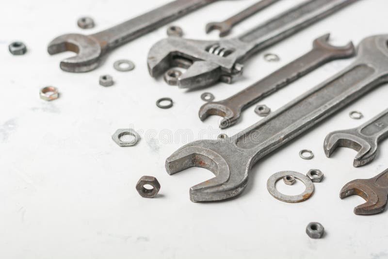 A lot of old wrenchs on a light stone background. Nuts and washers of different sizes. stock image