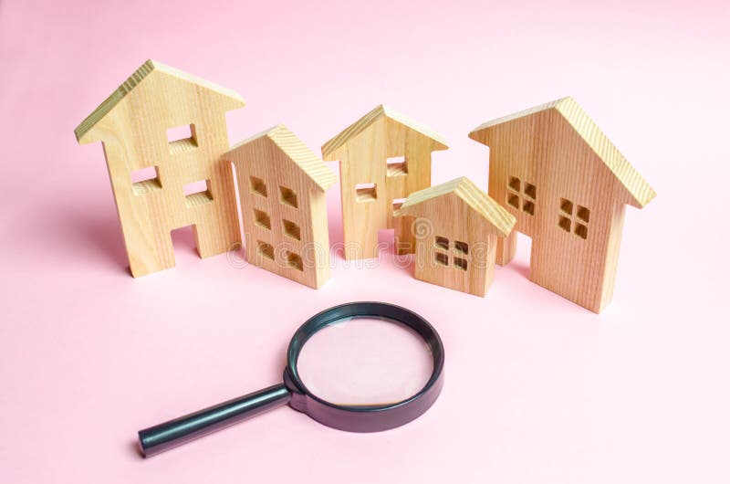 A lot of wooden houses on a pink background and a magnifying glass. The concept of finding a new home to buy or property to invest. Buying and selling real estate, investing. Romantic ancient city