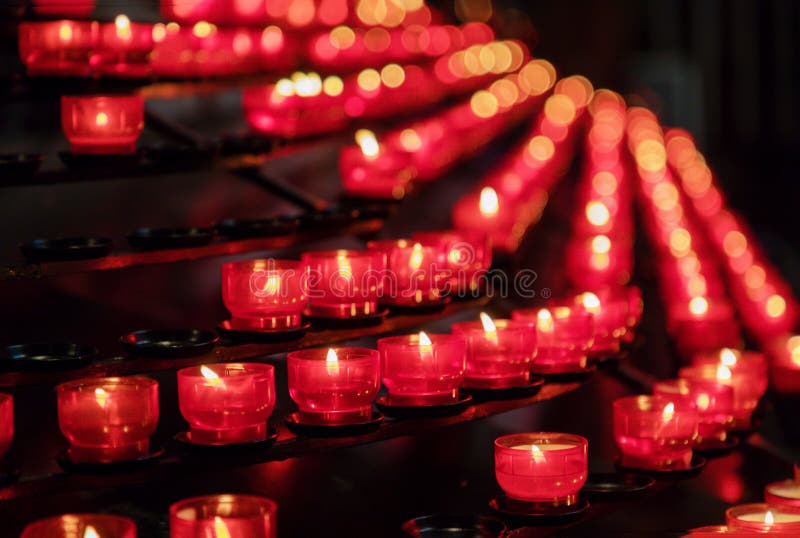 Lots of burning red candles in a church