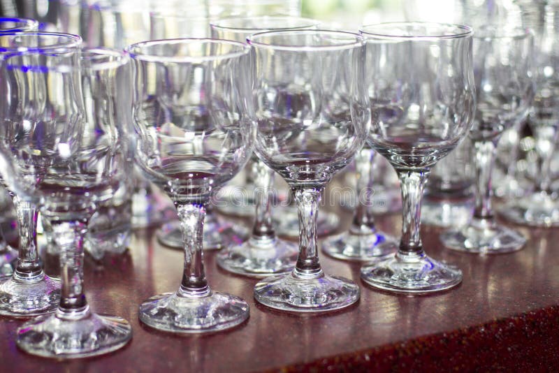 Lots of clean empty glasses of drinks on the bar in a nightclub. Glare and reflections on the glasses in the dark royalty free stock image Lots of clean empty glasses of drinks on the bar in a nightclub. Glare and reflections on the glasses in the dark royalty free stock image
