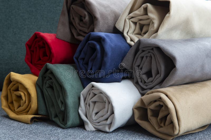 Many colorful rolls of fabric on a plain background royalty free stock images