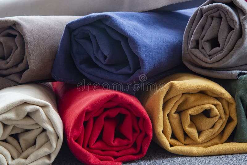 Many colorful rolls of fabric on a plain background royalty free stock photos