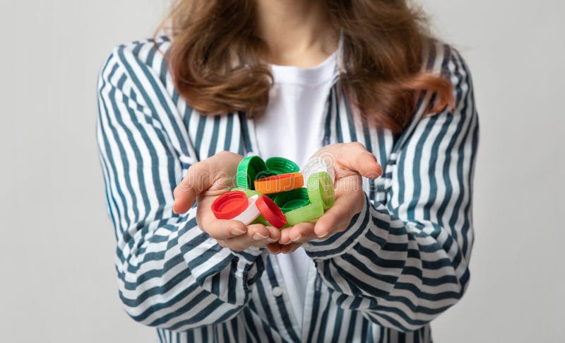 Lots Of Colorful Plastic Lids Bottle Caps In Hands Of Unrecognizable Female royalty free stock photo