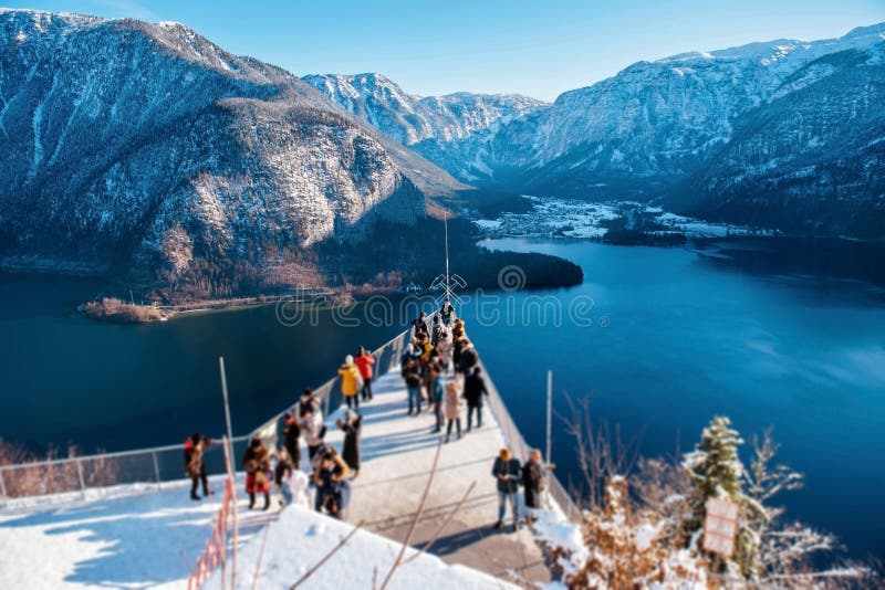 Tourists enjoying fascinating view of snowy Alps around lake. Lots of tourists standing on high place of Hallstatt town for enjoying fascinating view of snowy