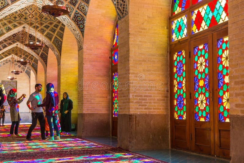 Lots of tourists taking photos in the interior of Nasir Al-Mulk Mosque Pink Mosque with colorful shining stained glass windows