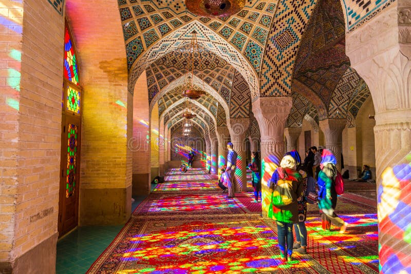 Lots of tourists taking photos in the interior of Nasir Al-Mulk Mosque Pink Mosque with colorful shining stained glass windows